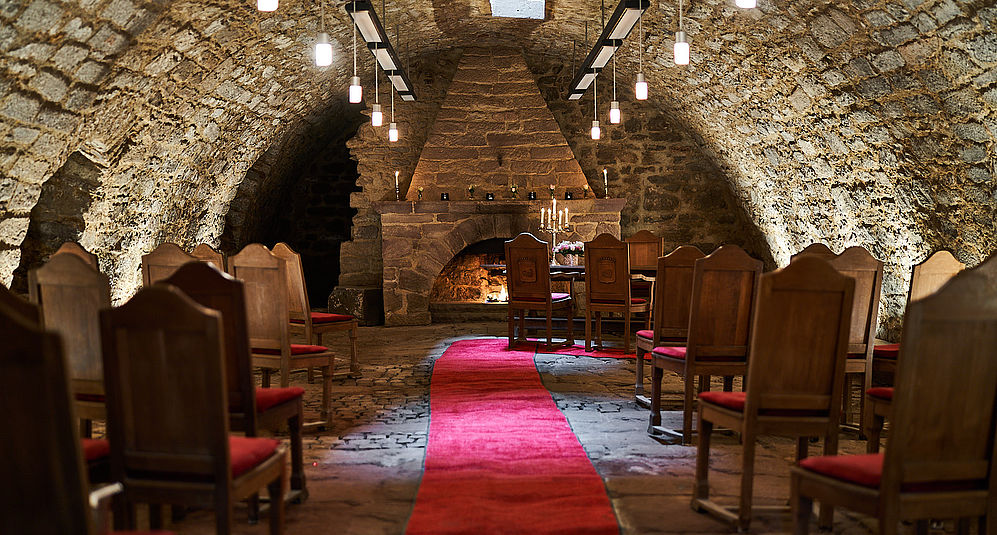 Festsaal für eine Hochzeit in Niedersachsen mit arrangierten Holzstühlen und einem roten Teppich