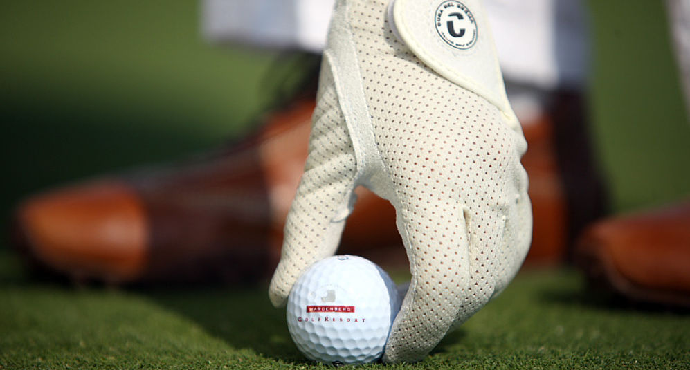 Die Hand einer Person beim Platzieren eines Golfballs im Golfurlaub in Niedersachsen.